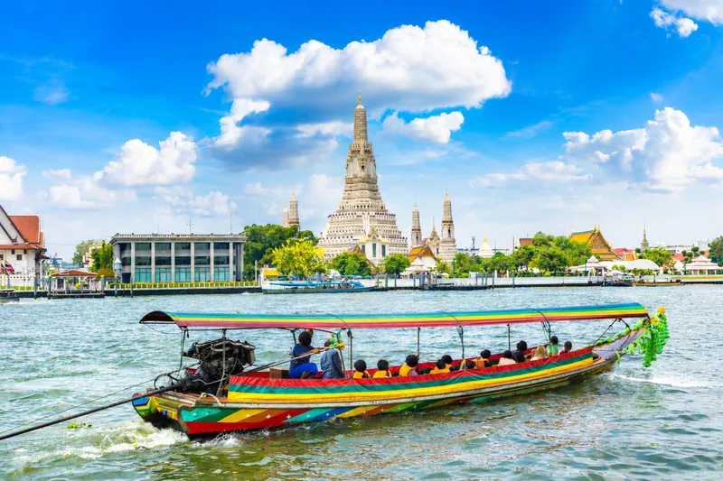 Local Bangkok canal with wooden stilt houses and a longtail boat passing on a private longtail boat tour through Thonburi khlongs